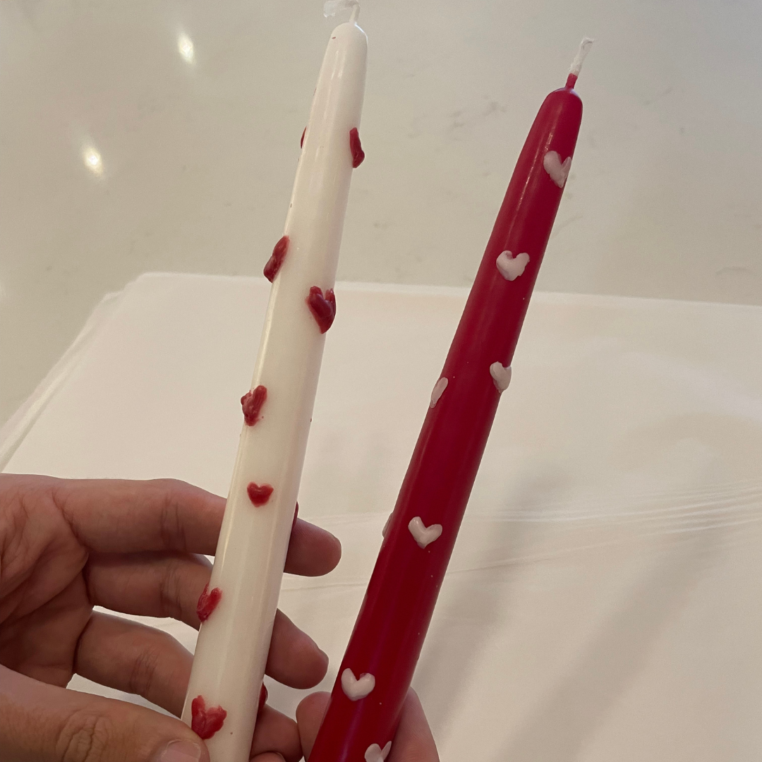 Two taper candles that have hearts painted on them from Far and Wide's Candle Painting event