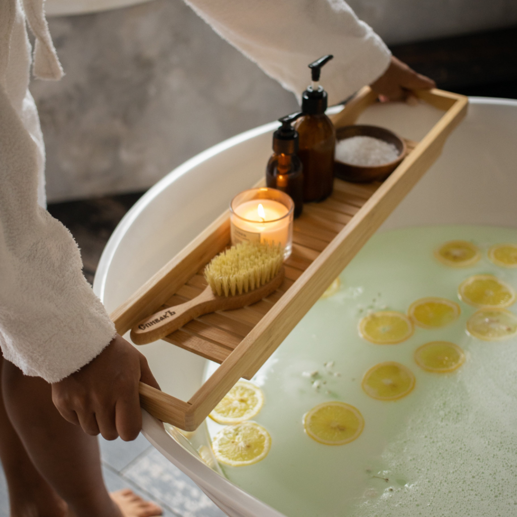 Preparing for a calming bath with bath and beauty products including a bath bomb, candle, brush, lotion, and soap