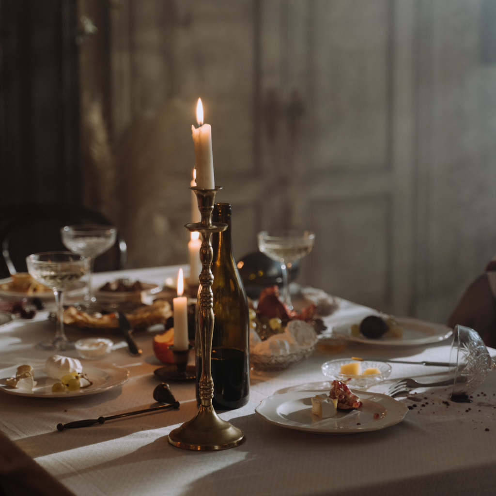 A table set up for a candlelight dinner with candles, wine, and food